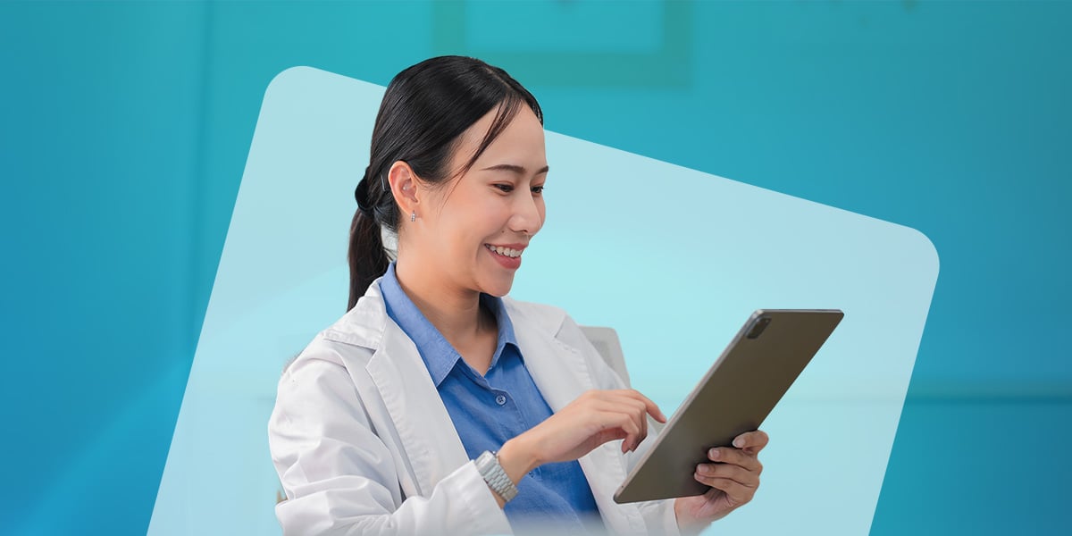 A female doctor with dark brown hair looks at a tablet